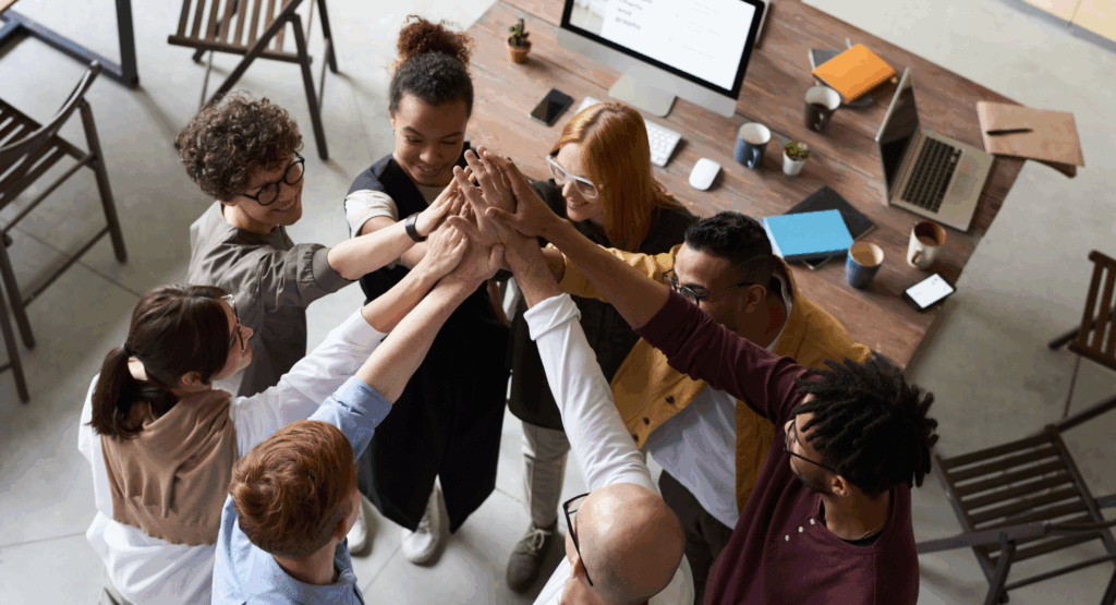 Equipo celebrando con las manos en alto en una oficina, simbolizando el éxito de una subvención internacionalización empresas Catalunya